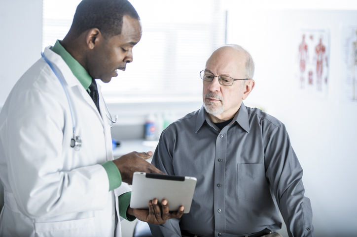 Photo shows a doctor speaking with a male patient