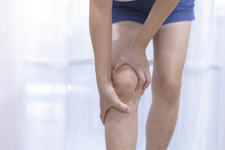 Photo shows woman holding knee in pain/Getty Images