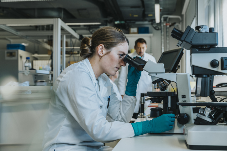 Photo shows a scientist in a laboratory looking at a sample through a microscope/Getty Images