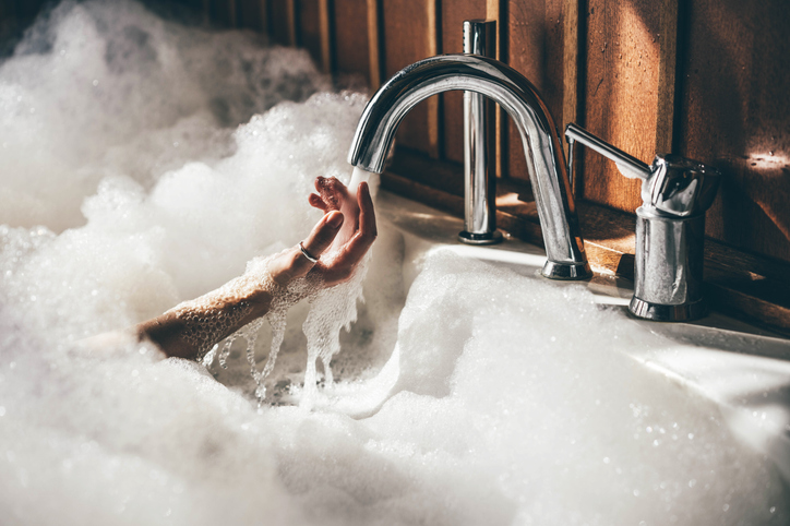 Photo shows woman holding her hands underwater in a bath/Getty Images