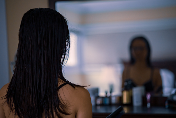 Photo shows a middle-aged woman looking at herself in the mirror/Getty Images