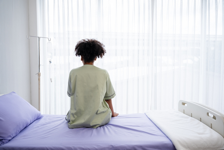 Photo shows a patient sitting on a hospital bed