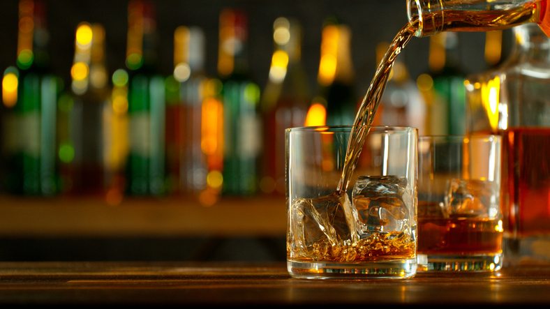 Photo shows a bartender pouring alcohol into glasses/Getty Images