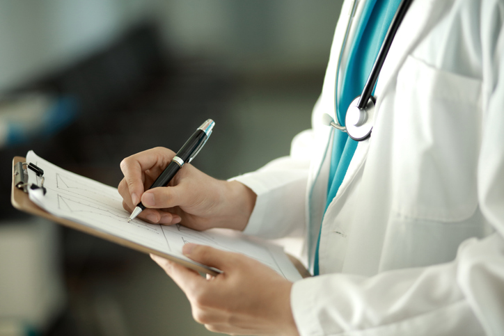 Photo shows a doctor writing on a clipboard/Getty Images