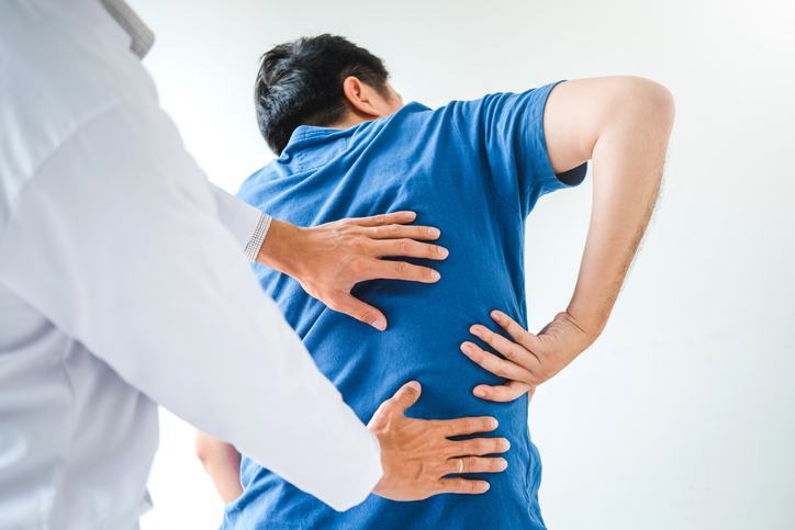 Photo shows doctor treating man with back pain