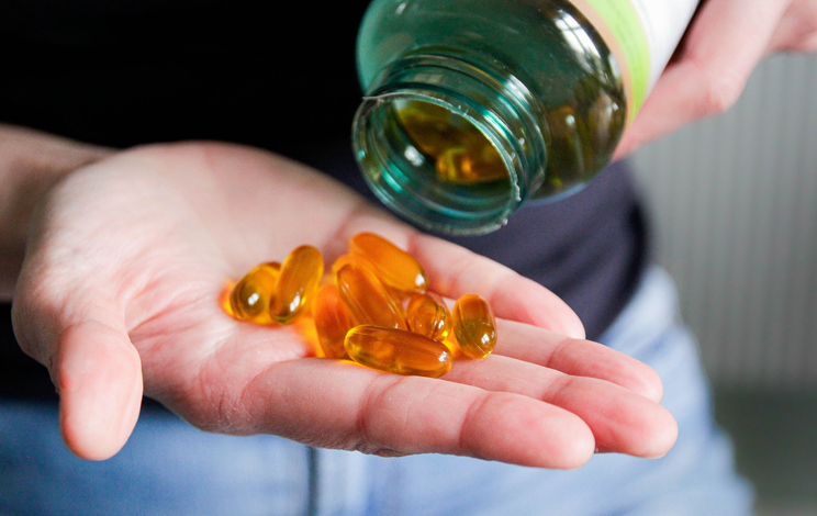 Photo shows Vitamin D supplements poured into a hand/Getty Images