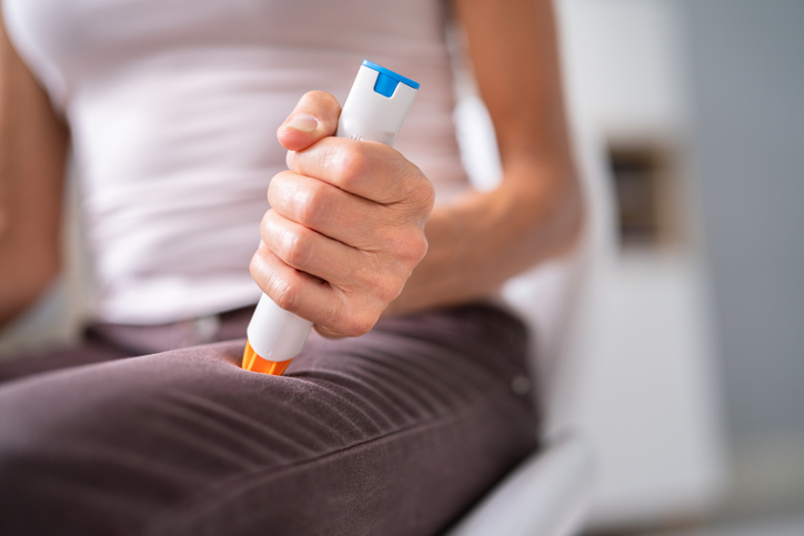 Photo shows a woman using an epinephrine injector to prevent anaphylaxis/Getty Images