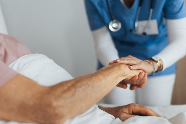 Photo shows a close-up of caregiver holding a senior patient's hand./Getty Images