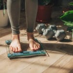 Photo shows a woman weighing herself.