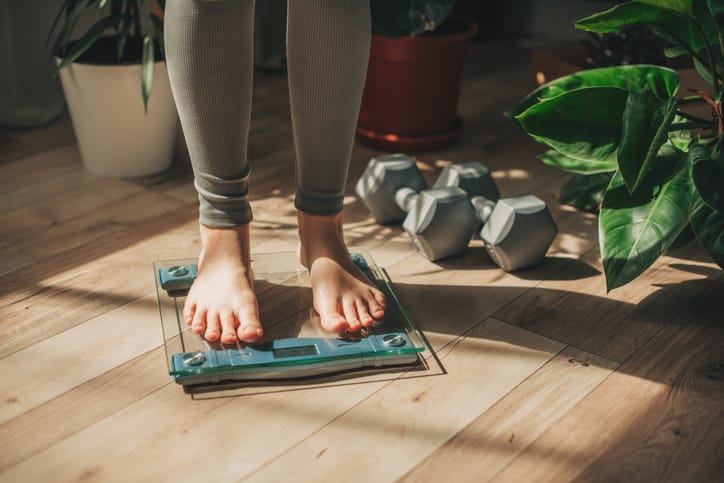 Photo shows a woman weighing herself.